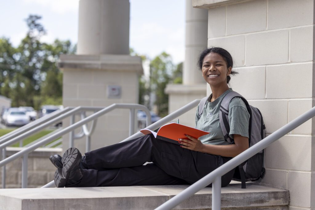 Student sitting outside with her notebook out.