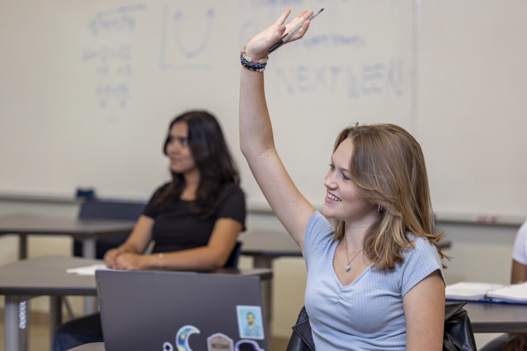 Female student raising her hand in a classroom setting