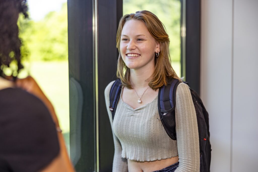 Female student smiling while talking to a friend.
