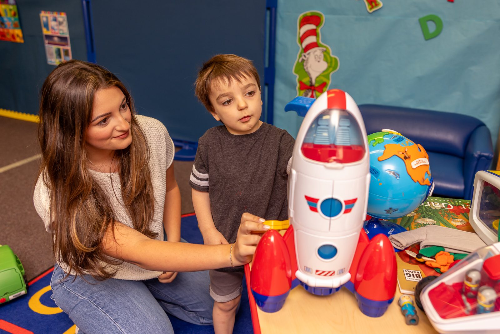 A female student and a young boy playing with toys.