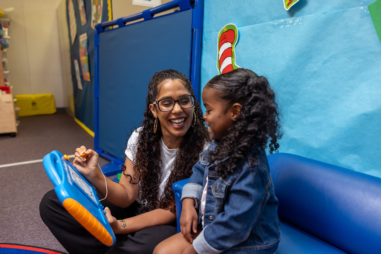 A female student reading a book to a young girl.